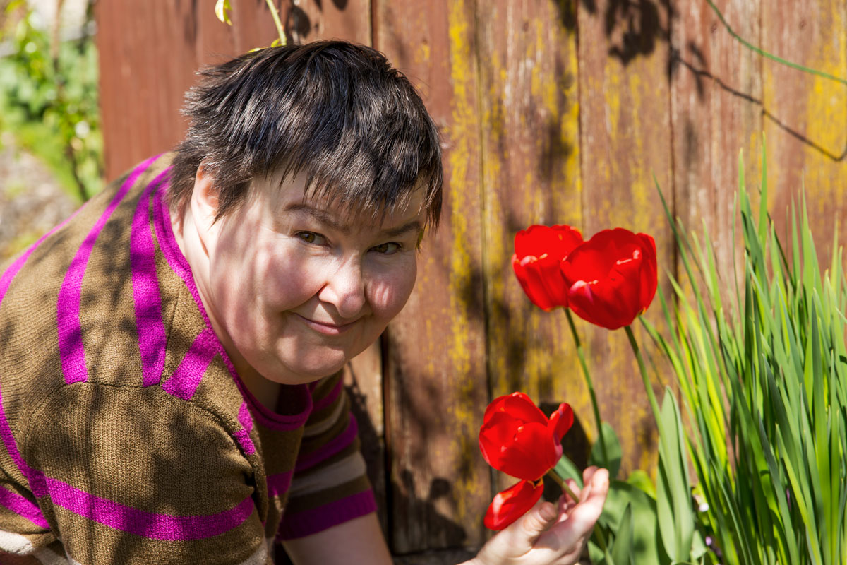 Damen-mit-Blume-in-der-Hand-bei-einer-Holzwand