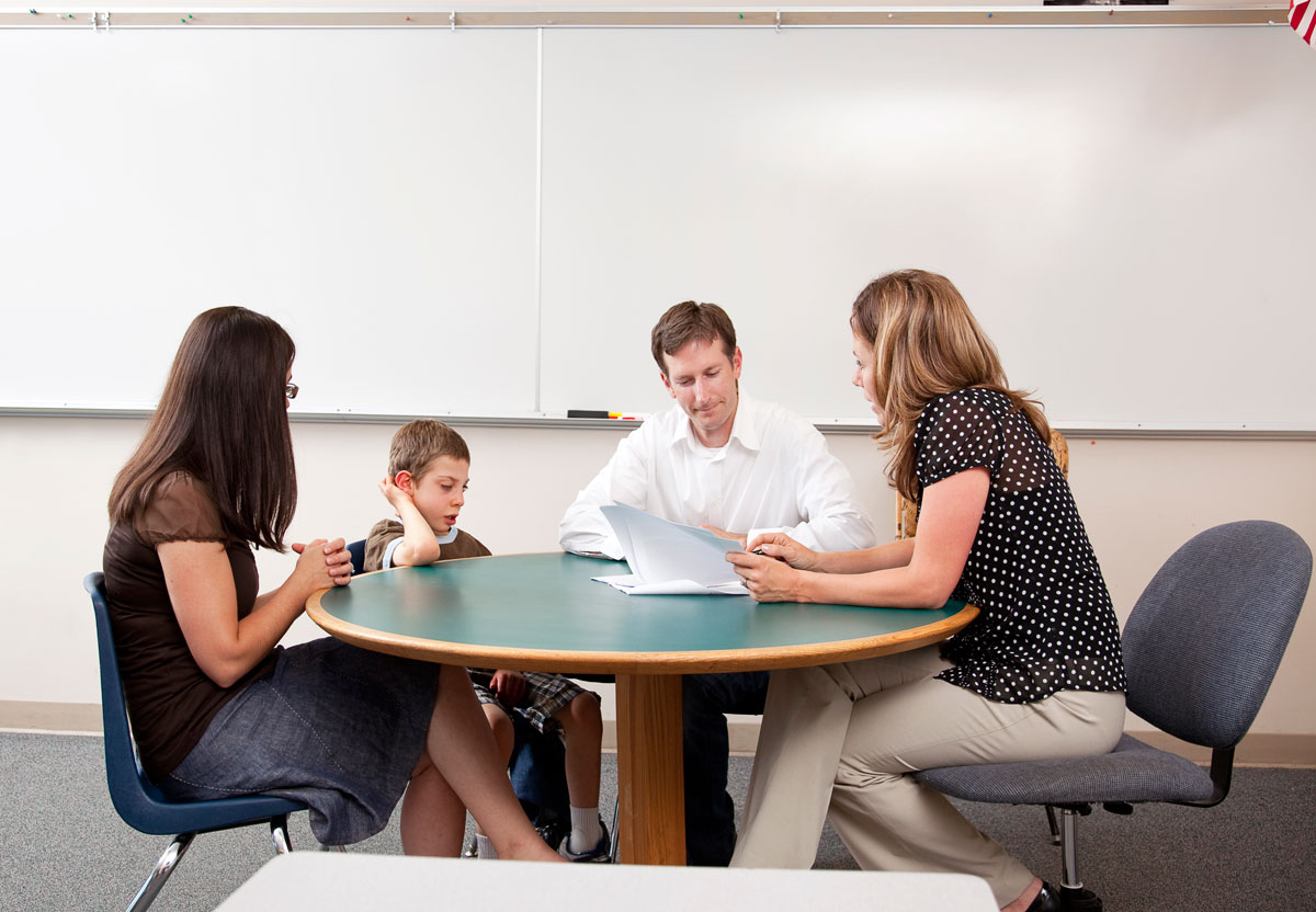 Drei-Erwachsene-und-ein-Kind-sitzen-bei-einem-runden-Tisch-und-Besprechen-ein-Dokument